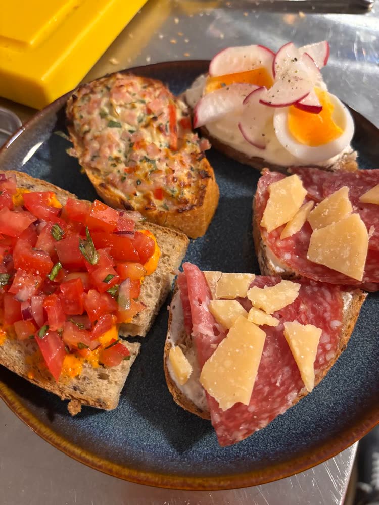 Bruschetta, Salami und Parmesan auf dunklem Teller
